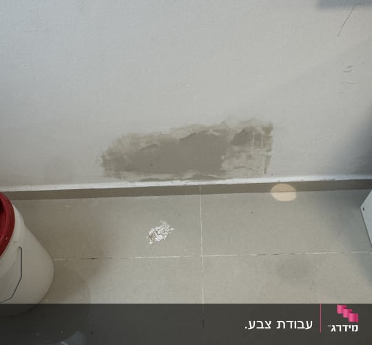 קיר עם תיקון טיח ודלי צבע על הרצפה